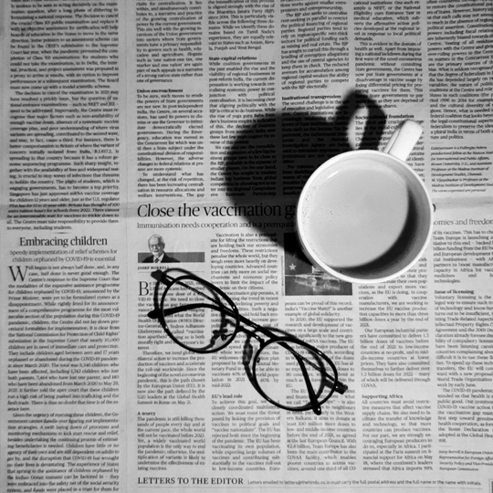 pair of glasses and a coffee cup on top of a news paper